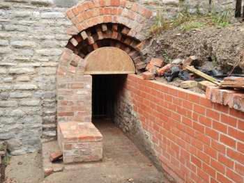 A wooden former is in place during the rebuilding of a brick arch in a stone wall