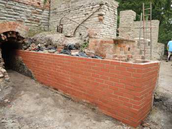 Rebuilt brick wall in front of stone wall