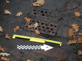 Two perforated bricks lie at the bottom of a brick structure.