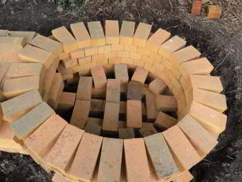 A view inside a circular structure made from light-coloured bricks.  The bricks making up the bottom are laid in an open pattern.