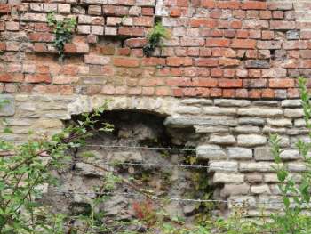 Rebuilt section of a wall with a stone facing below and brick on top