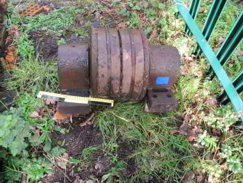 A metal object sits on grass, with a blue label on its right.